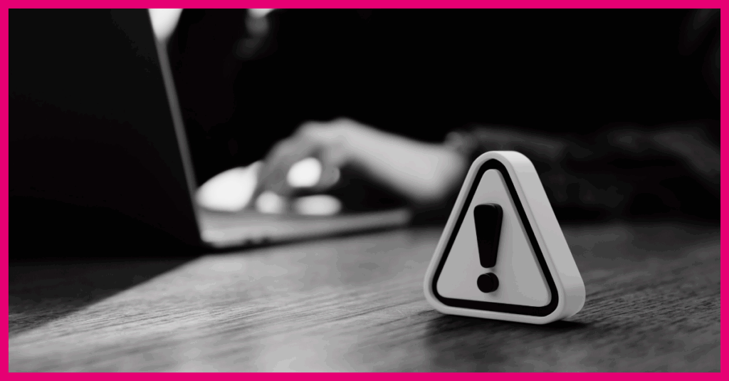 a warning sign in the foreground, a person working on a laptop in the background