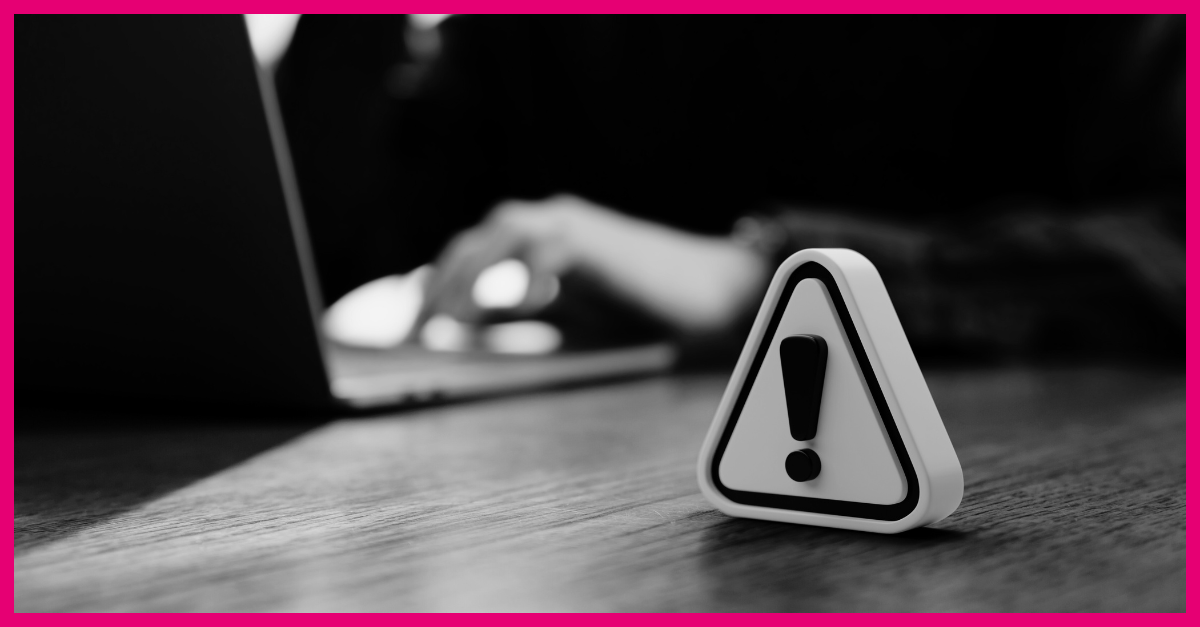a warning sign in the foreground, a person working on a laptop in the background